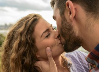 Swipe Safer: How to Spot and Avoid Hookup App Scams Close-up of a couple sharing a passionate kiss outdoors, capturing a moment of romance and affection.