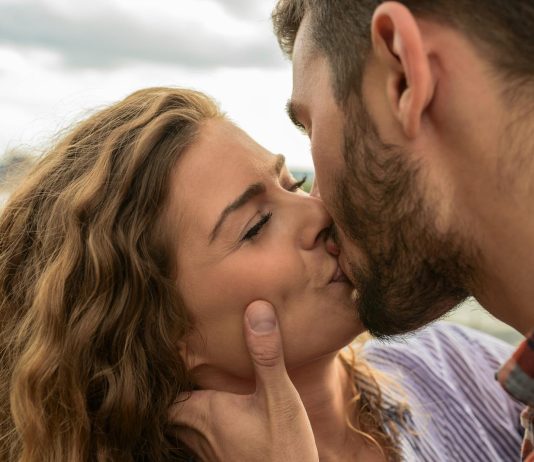 Swipe Safer: How to Spot and Avoid Hookup App Scams Close-up of a couple sharing a passionate kiss outdoors, capturing a moment of romance and affection.