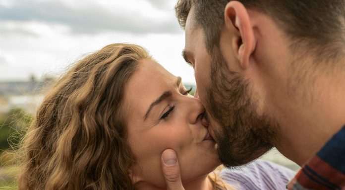Swipe Safer: How to Spot and Avoid Hookup App Scams Close-up of a couple sharing a passionate kiss outdoors, capturing a moment of romance and affection.