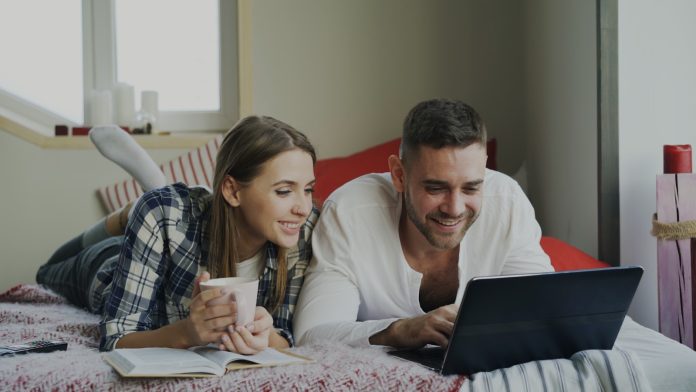 Couple looking at a laptop on a bed